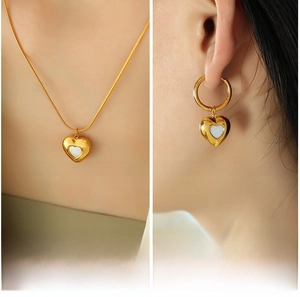 Detail of heart shell necklace and earrings set in gold with white mother-of-pearl
