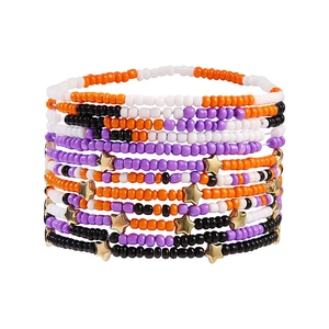 Detail view of multi-layer beaded bracelets with gold star charms in Halloween colors