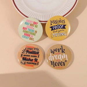 Detail of four vintage tinplate badges with inspirational English quotes in warm tones