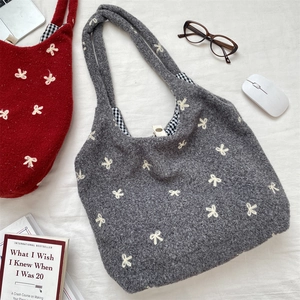 Detail of embroidered bow on knit tote bag with vichy plaid lining and snap closure