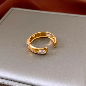 Macro shot of gold adjustable ring with drop-shaped and round zircon stones on a gray stand