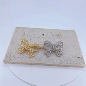 Détail de pendentifs nœuds en or et argent sertis de zircons sur pierre texturée
