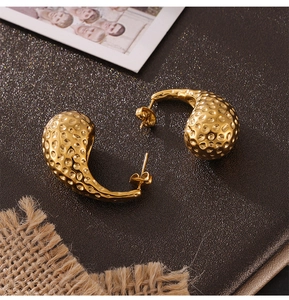 Vue détaillée de boucles d'oreilles gouttes d'or avec texture martelée en acier titane pur