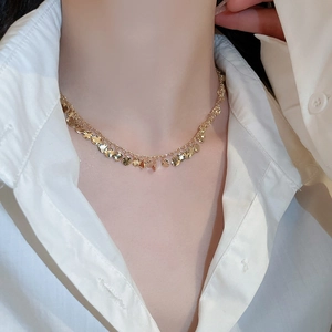 Detail of gold geometric wavy sequin fringe choker on model with white shirt