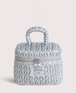 Detail of silver quilted makeup bag with wave pattern and pearl zipper charms