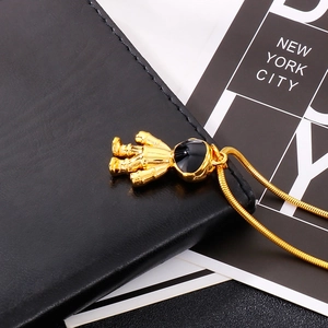 Detail of golden astronaut pendant with black gemstone on sleek snake bone chain