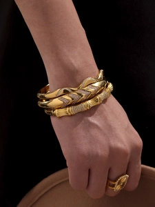 Detail of stacked 18k gold plated bamboo texture and wave zircons bracelets on wrist