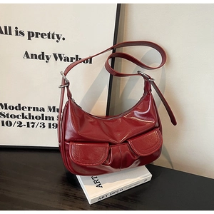 Detail of burgundy hobo bag showing glossy patent leather and front flap pockets