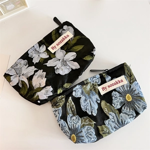Close-up of floral jacquard pouches in black with white and blue flower patterns