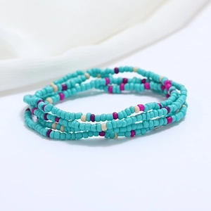 Close-up of turquoise and pink layered seed bead waist chain on white fabric background
