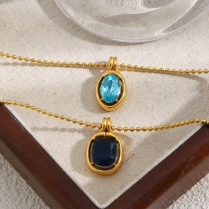 Detail of 18K gold-plated bead necklaces with light and dark blue oval gemstones in a box