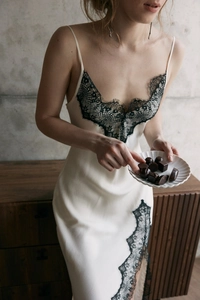 Détail de la dentelle noire et du satin de soie sur une nuisette blanc crème