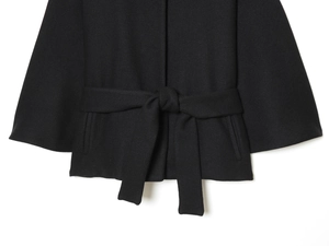 Detail of black wool jacket with textured twill fabric and knotted waist belt design