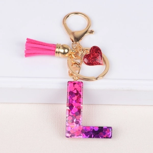 Detailed macro view of pink glitter resin letter L keychain with fuchsia suede tassel