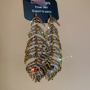 Detailed view of silver needle luxury leaf feather drop earrings with sparkling rhinestones