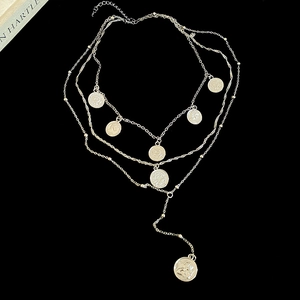 Detailed view of layered gold coin pendant necklace featuring multi-strand chains and vintage coins