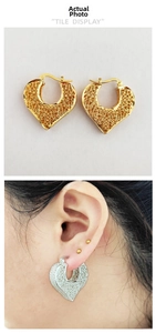 Detail view of gold and silver heart hoop earrings with intricate filigree texture