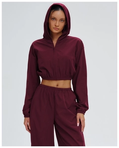 Detail view of wine red zip-up hooded sports jacket with elastic cuffs and windproof fabric