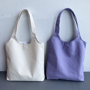 Detail view of durable canvas tote bags in cream and purple with sturdy handles