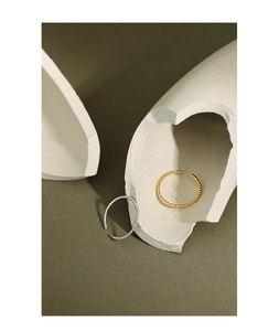 Macro detail of gold and silver minimalist beaded spiral rings on stone base