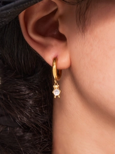 Close-up of a 18k gold plated hoop earring with a cubic zirconia teddy bear pendant