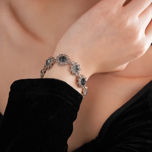 Detail of vintage-style flower bracelet with dark grey rhinestones on model's wrist