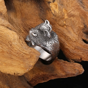 Detailed close-up of double wolf head vintage steel ring on natural wood texture