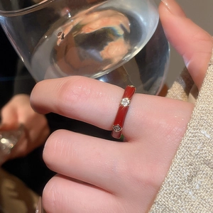 Detail of a red enamel ring with gold plating and zircons worn on a finger