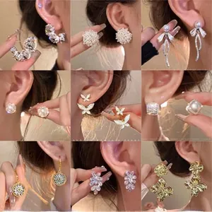 Collection of nine gold earrings with pearls, crystals and butterfly designs shown on model