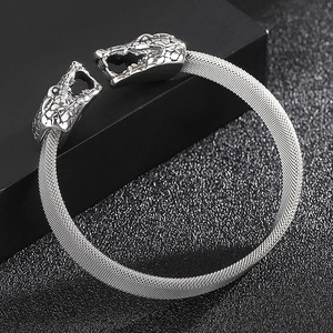 Detail of silver snake head terminal and mesh texture on stainless steel bangle