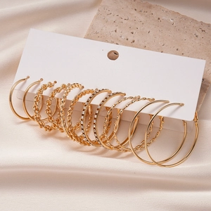 Detailed set of six pairs of gold hoop earrings with rhinestones on white card display