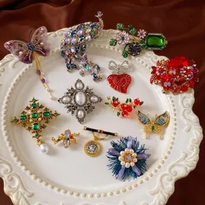 Detail of vintage style brooches with colorful crystals and pearls on red silk background