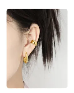 Detail view of gold U-shaped earrings with irregular textured surface on female model