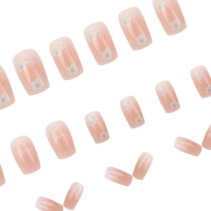 Short square press-on nails featuring nude pink gradient and cute white floral patterns