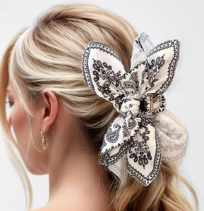 Detail of white paisley bandana bow on a gold shark hair clip worn by a model