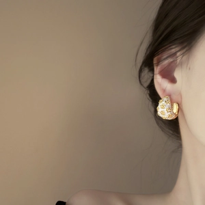 Vintage gold and white enamel C-shaped flower earrings worn by a model in a luxury style
