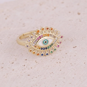 Gold Evil Eye ring with colorful cubic zirconia stones on a minimalist stone background