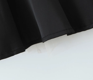 Détail du tissu en satin noir avec des couches d'ourlet en dentelle de maille blanche