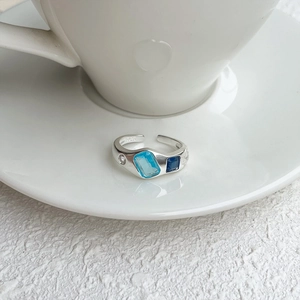 Detail of S925 silver adjustable ring featuring blue gems and white zircon on ceramic