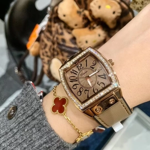 Detailed view of women's gold barrel-shaped watch with diamond bezel and beige leather strap