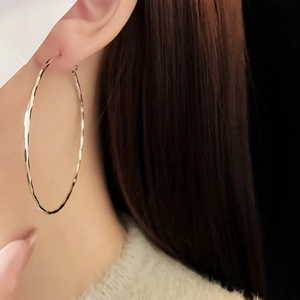 Close-up of a silver hammered hoop earring on a model with shimmering metal texture