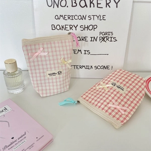 Close-up of checkered fabric makeup bags with cute ribbon bows and brand labels