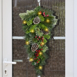 Close-up of Christmas teardrop swag with pine cones and LED lights on a white door
