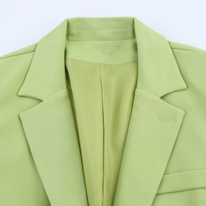 Détail d'un blazer vert clair montrant le revers à encoche et la texture du tissu sergé