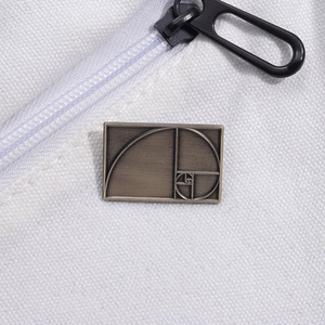 Golden ratio Fibonacci spiral brooch in bronze metal pinned on a white canvas backpack