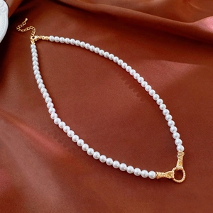 Detailed view of pearl necklace with gold clasp on silk fabric, elegant fashion accessory