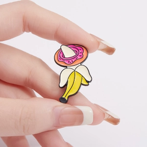 Creative banana donut enamel brooch held in hand against a white background