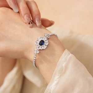 Detailansicht eines silbernen Blumenarmbands mit blauem Zirkon und weißen Steinen