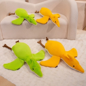 Detailed plush pterosaur toy featuring soft green fabric and spread wings on a white sofa