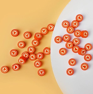 Macro detail of orange polymer clay bead with white heart pattern for jewelry making